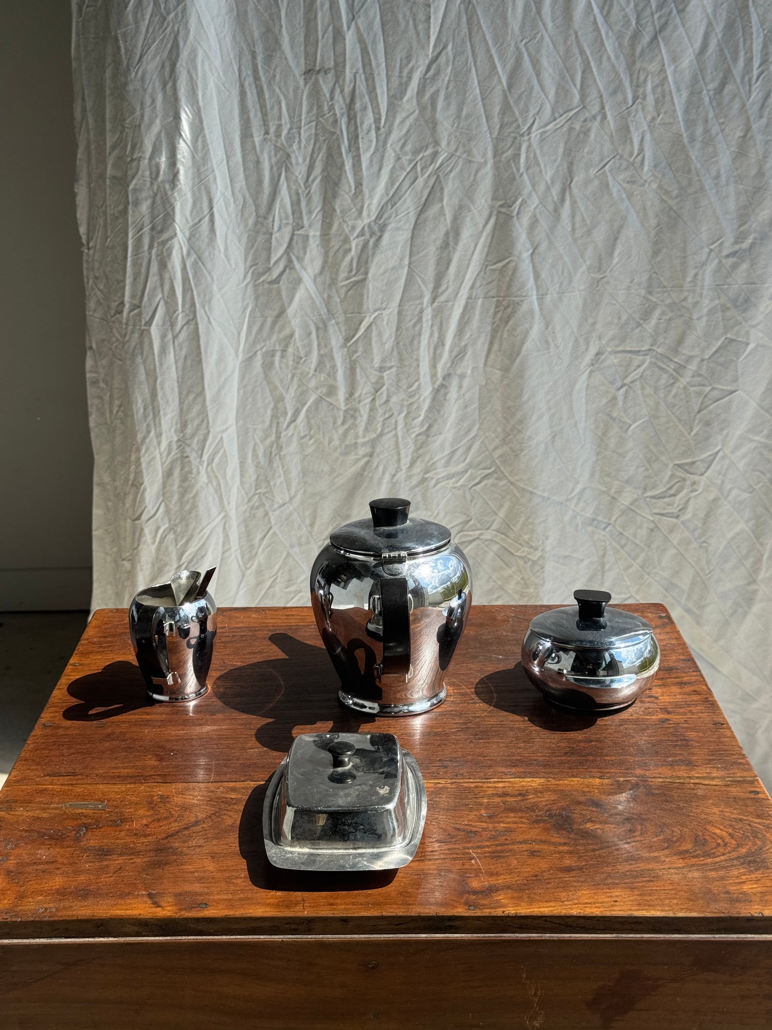 Service à thé comprenant une théière, un pot à lait, un sucrier et un beurrier en métal argenté et poignées noires