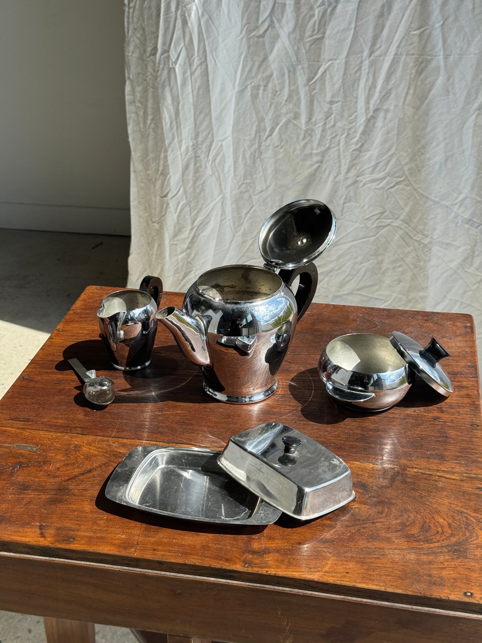 Service à thé comprenant une théière, un pot à lait, un sucrier et un beurrier en métal argenté et poignées noires