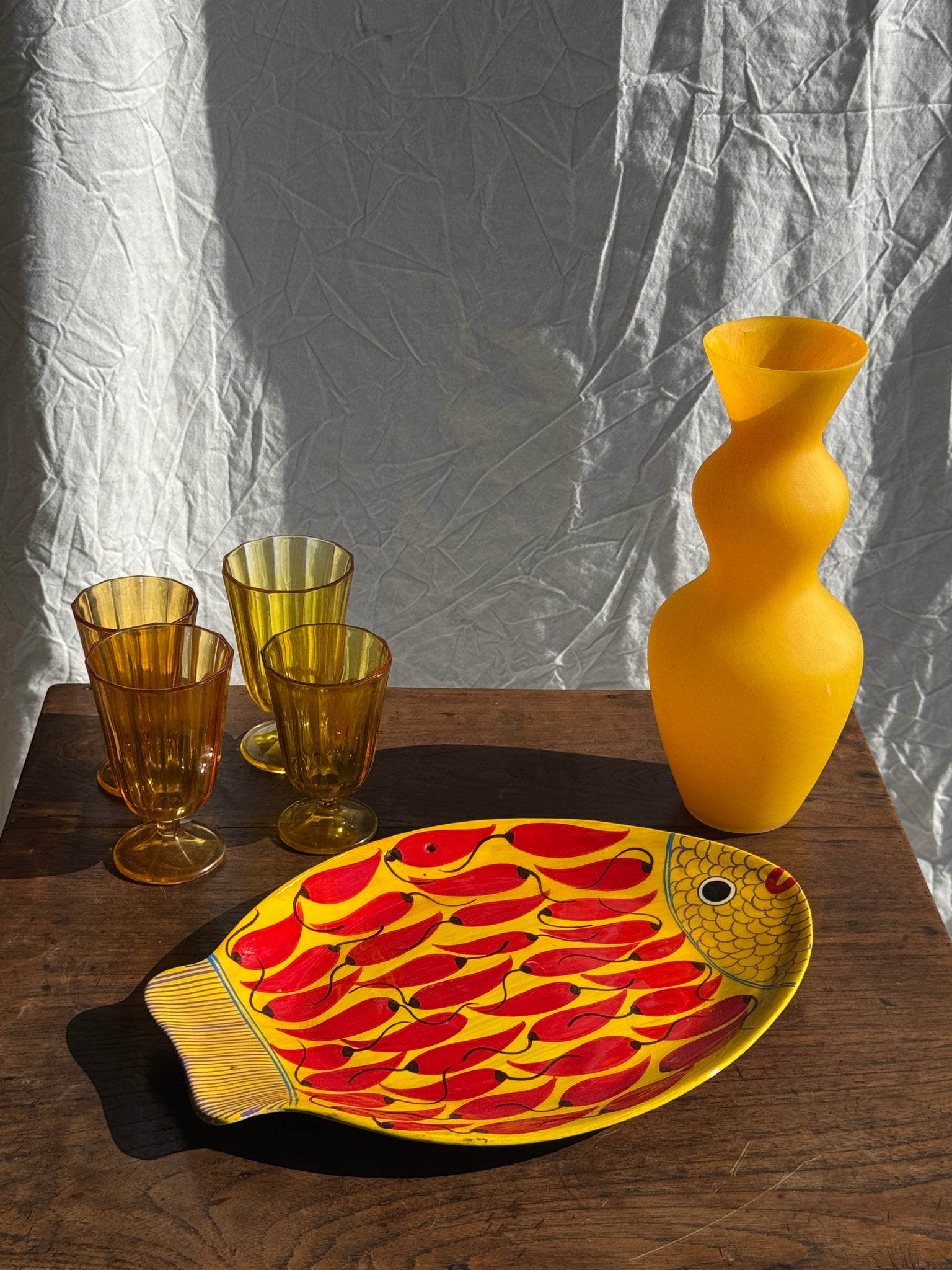 Plat décoratif en forme de poisson fond jaune à décor de piments rouges