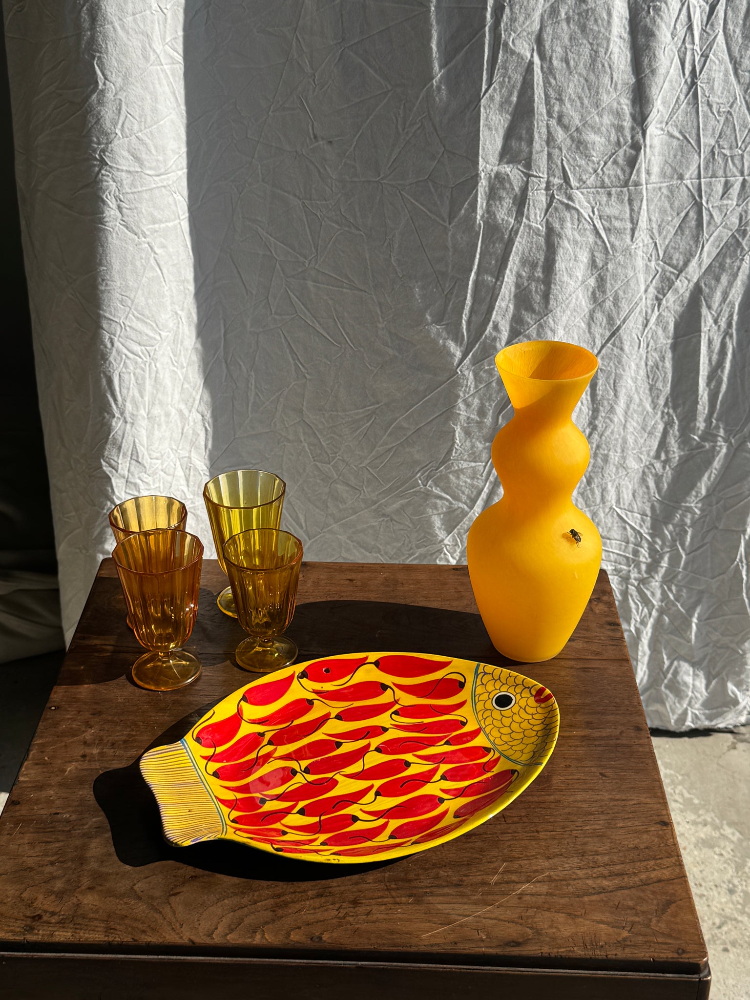 Plat décoratif en forme de poisson fond jaune à décor de piments rouges