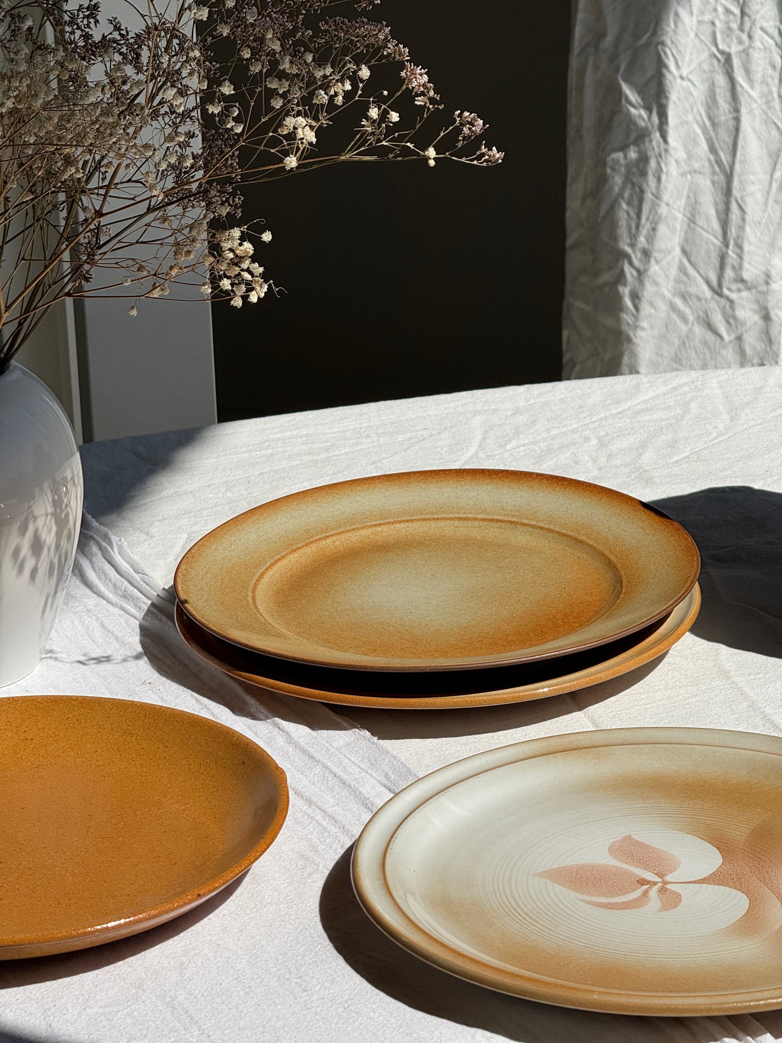 Réunion de 4 assiettes en grès vintage dont 2 avec des motifs de fleurs stylisées