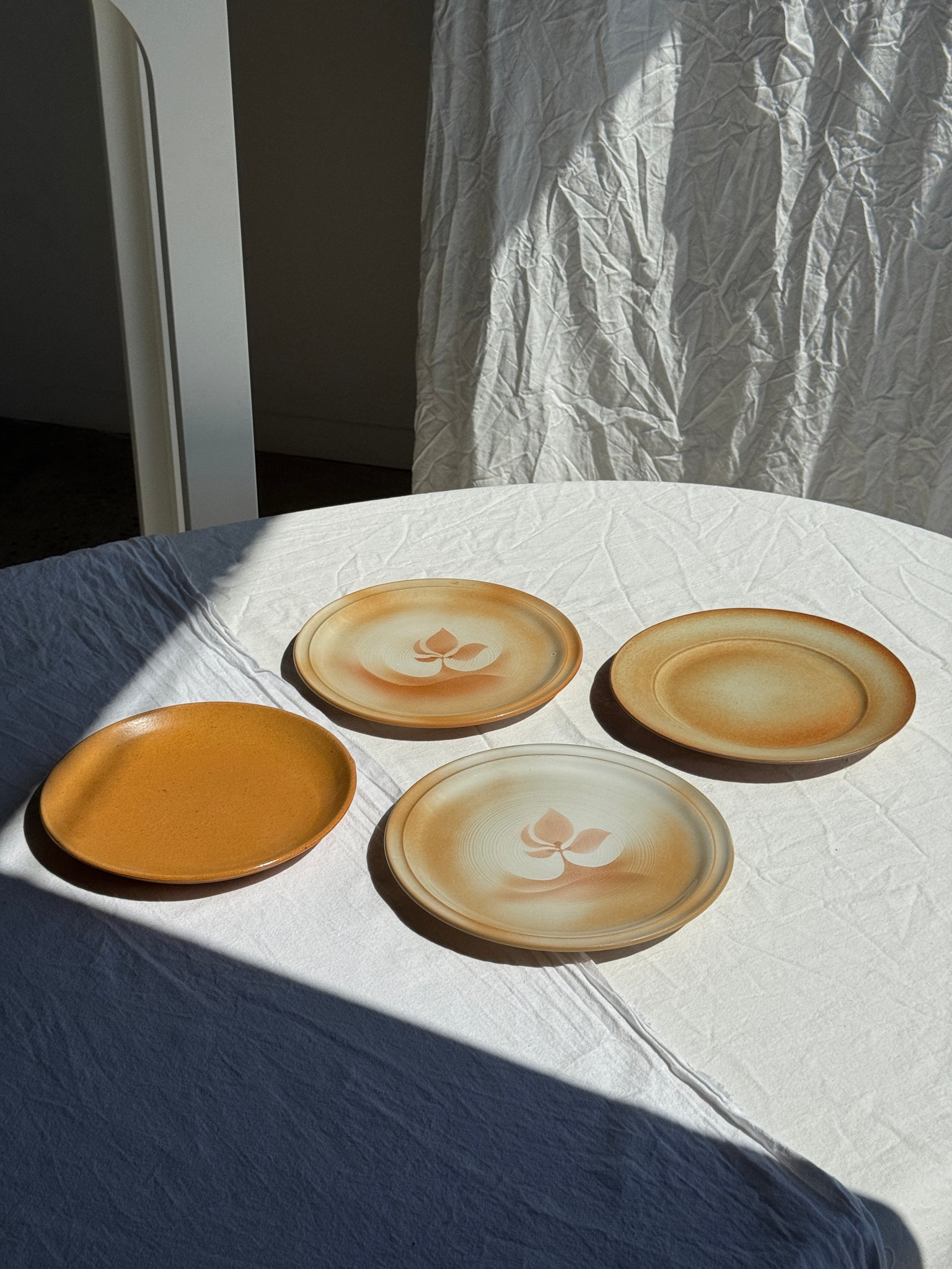Réunion de 4 assiettes en grès vintage dont 2 avec des motifs de fleurs stylisées
