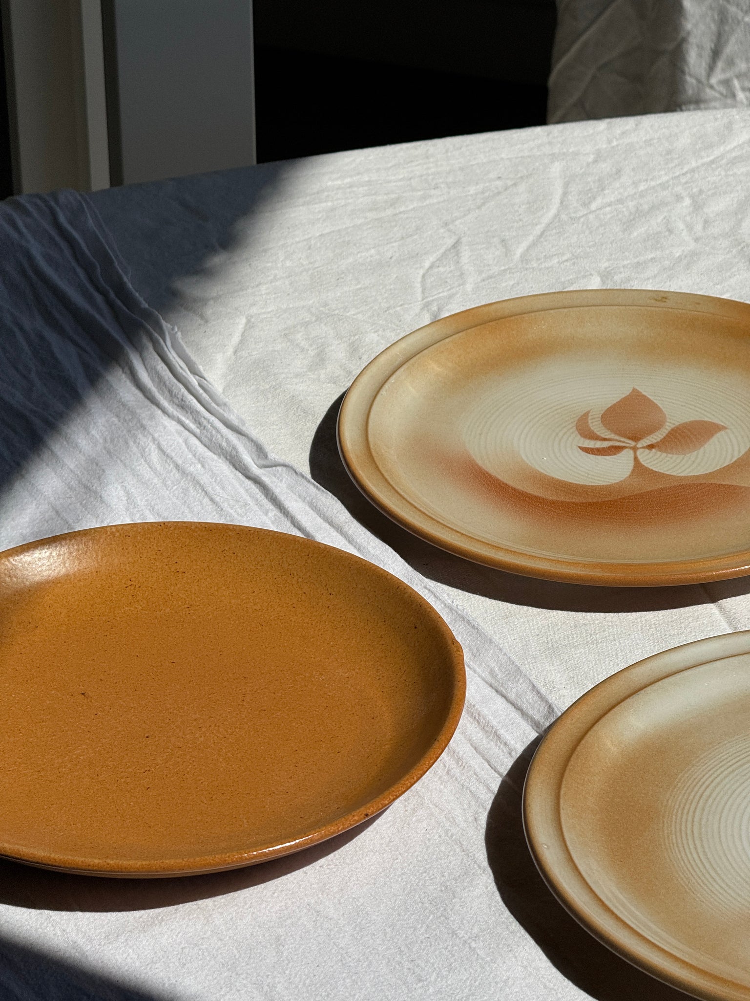 Réunion de 4 assiettes en grès vintage dont 2 avec des motifs de fleurs stylisées