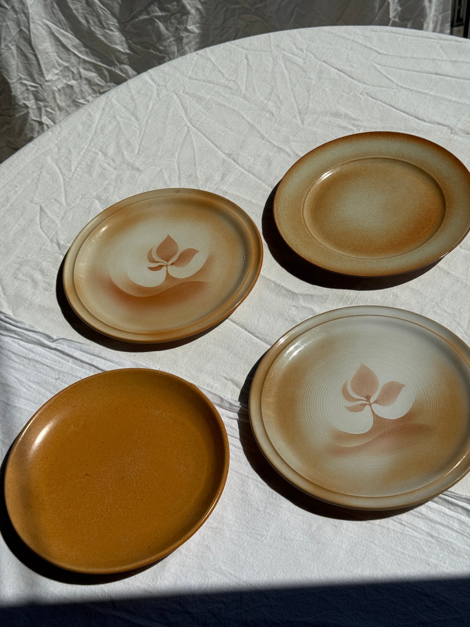 Réunion de 4 assiettes en grès vintage dont 2 avec des motifs de fleurs stylisées