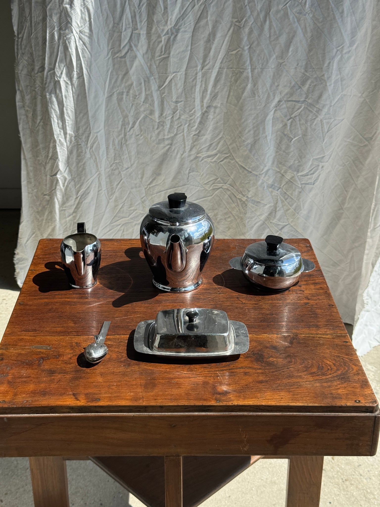 Service à thé comprenant une théière, un pot à lait, un sucrier et un beurrier en métal argenté et poignées noires