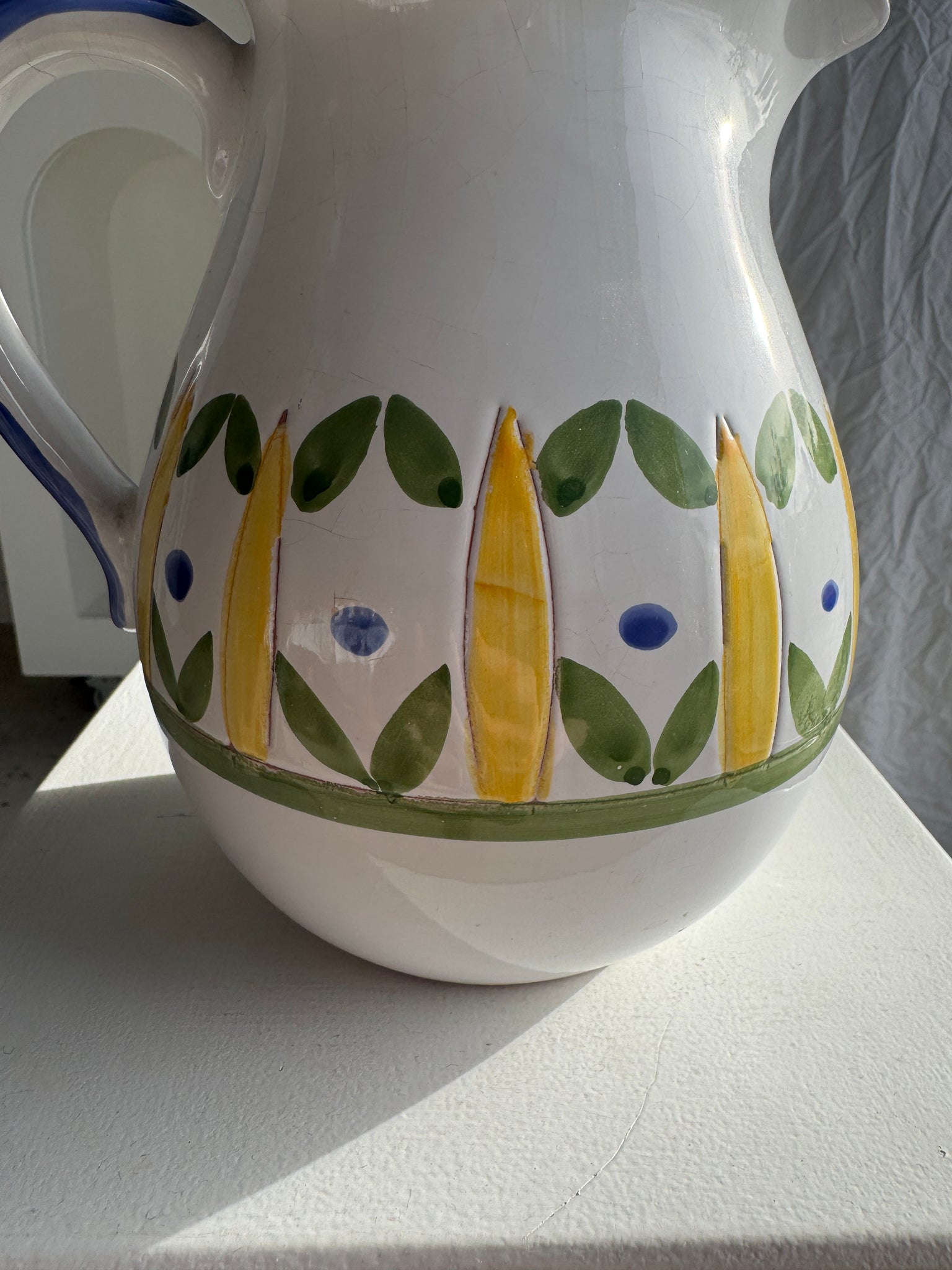 Grande carafe blanche en terre cuite à motif de frise stylisée verte jaune et bleue H20 D17