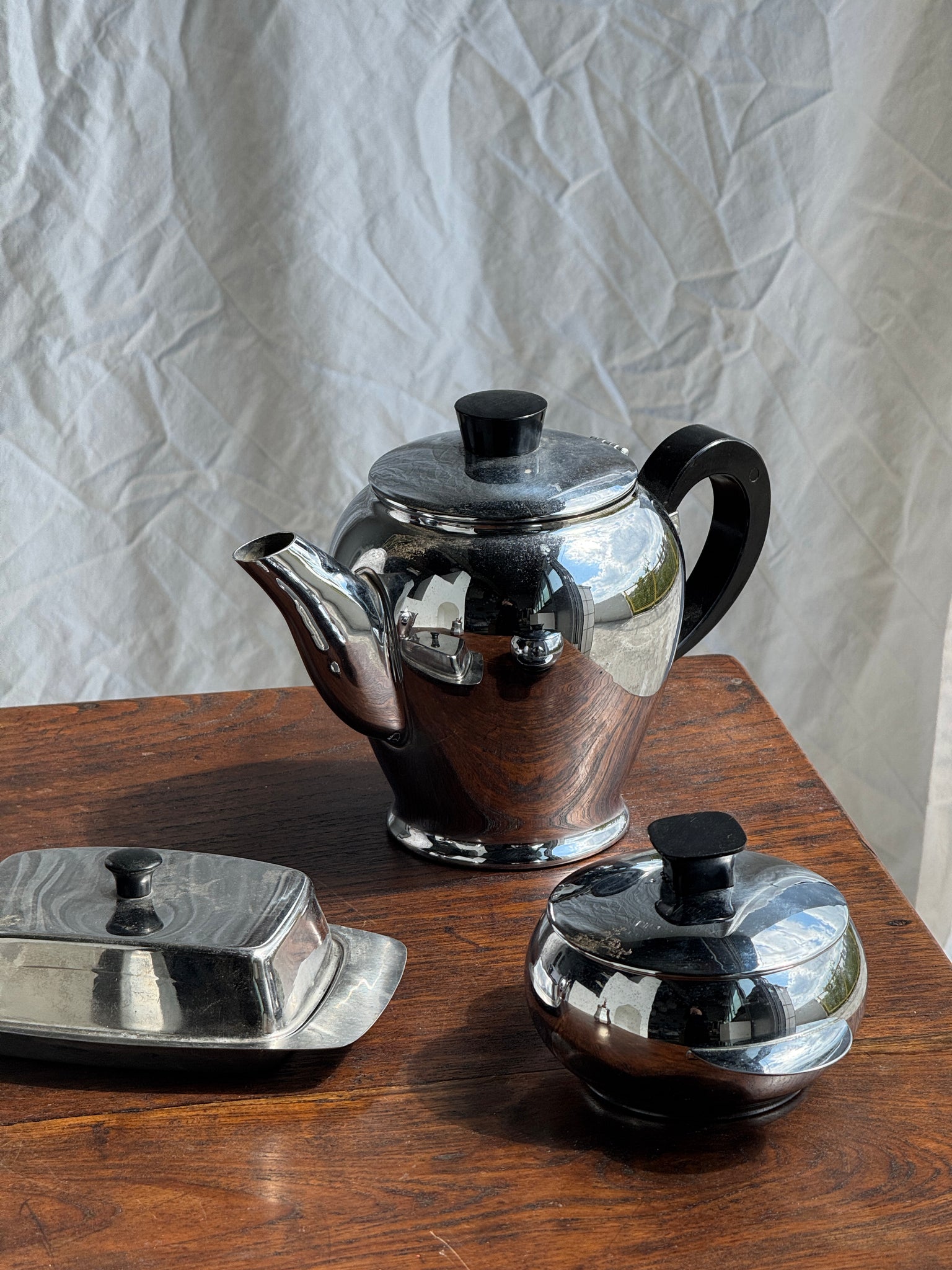 Service à thé comprenant une théière, un pot à lait, un sucrier et un beurrier en métal argenté et poignées noires