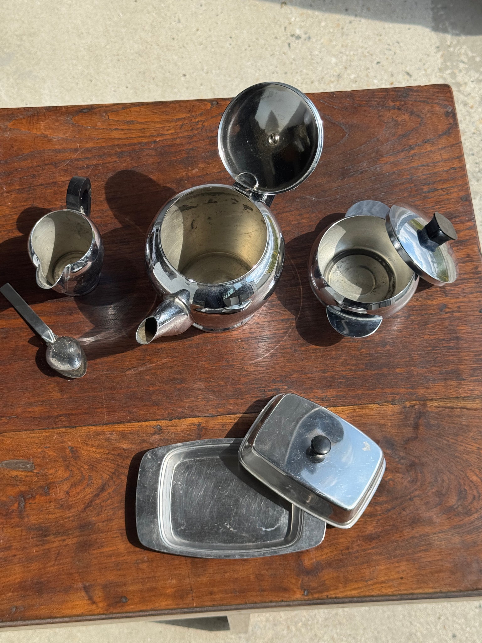 Service à thé comprenant une théière, un pot à lait, un sucrier et un beurrier en métal argenté et poignées noires