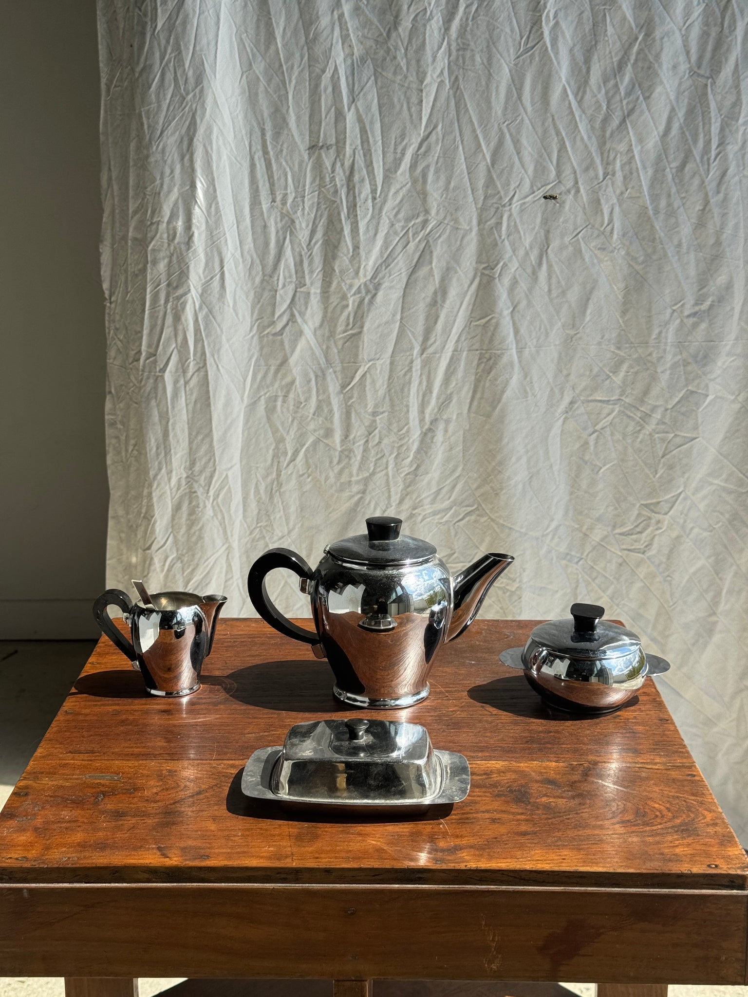 Service à thé comprenant une théière, un pot à lait, un sucrier et un beurrier en métal argenté et poignées noires