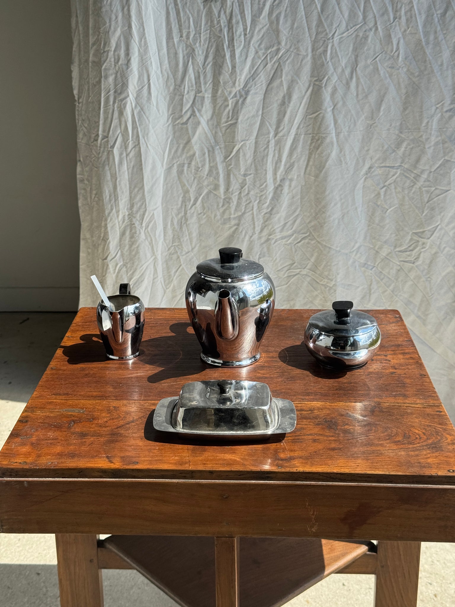 Service à thé comprenant une théière, un pot à lait, un sucrier et un beurrier en métal argenté et poignées noires