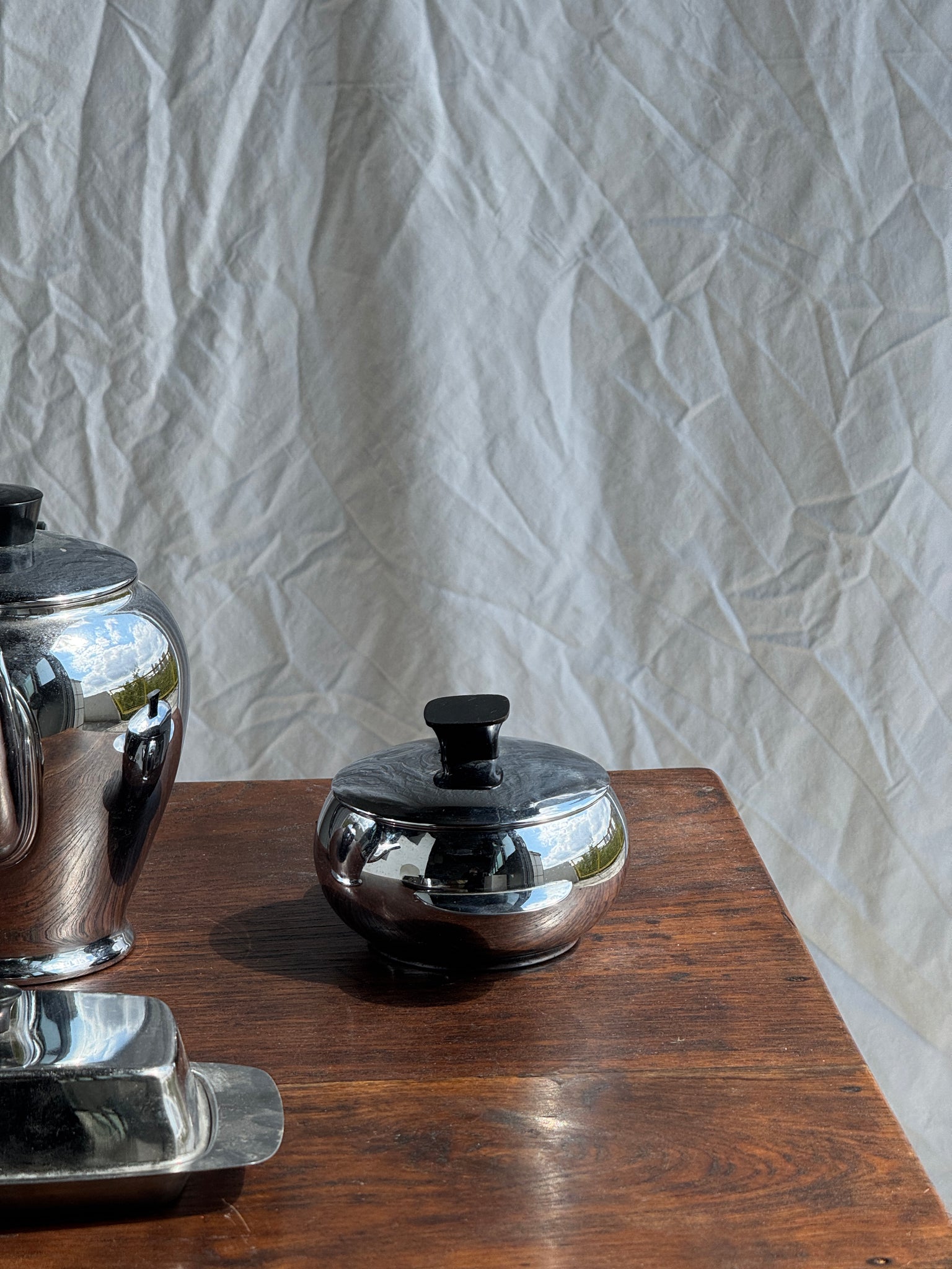 Service à thé comprenant une théière, un pot à lait, un sucrier et un beurrier en métal argenté et poignées noires