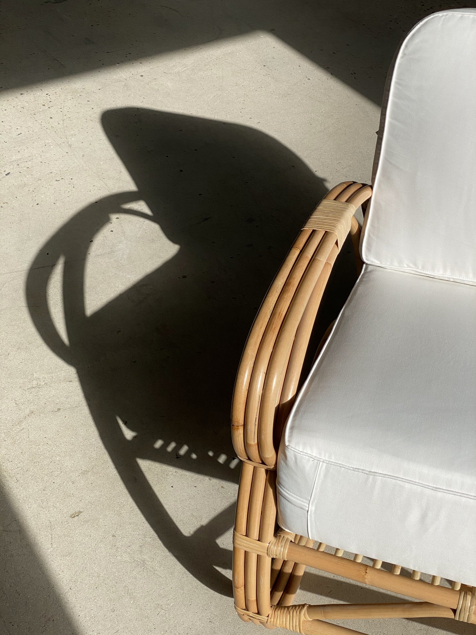 Grand fauteuil de repos en rotin et coussins blancs