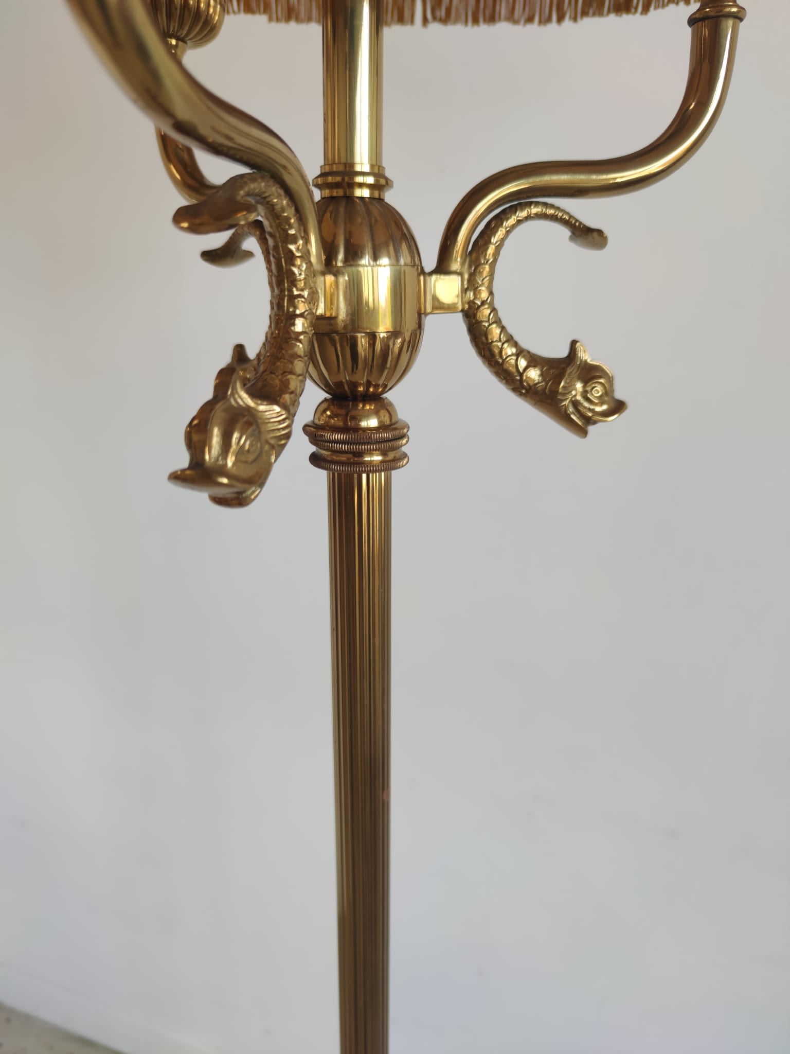 Lampadaire tripode en métal doré à trois bras de lumière, décor de dauphins et abat-jour ocre à franges