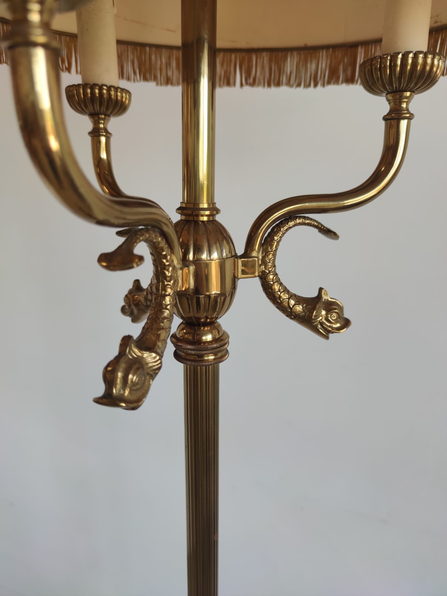 Lampadaire tripode en métal doré à trois bras de lumière, décor de dauphins et abat-jour ocre à franges